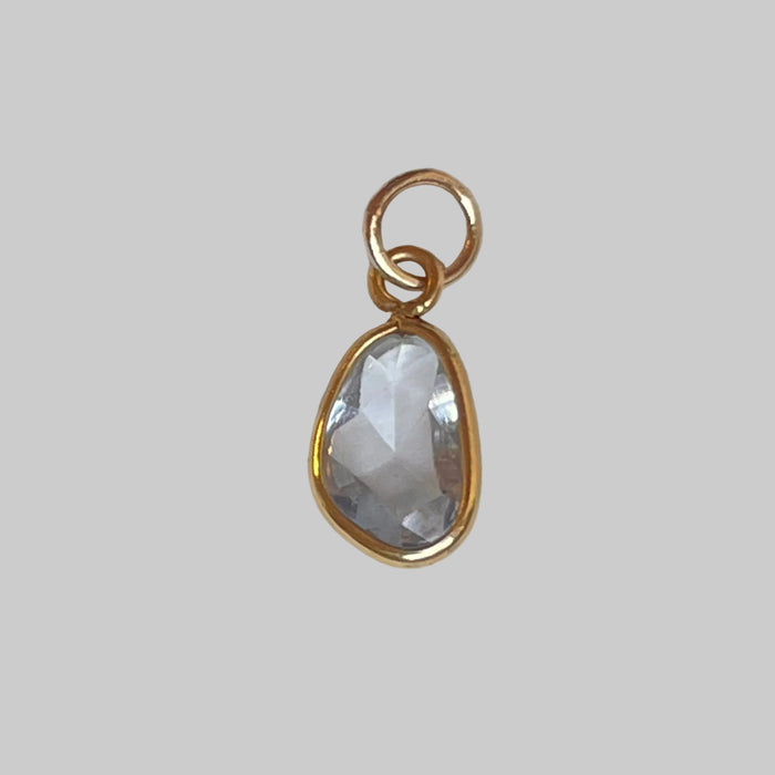 Gold pendant with a clear teardrop-shaped gemstone on a light gray background