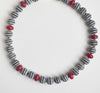 Necklace with striped beads and red accents on a white background