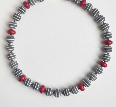Necklace with striped beads and red accents on a white background