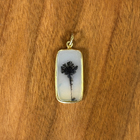 Rectangular pendant with tree design on a wooden surface