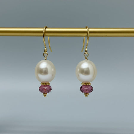 Pair of pearl earrings with pink tourmalines on a gray background