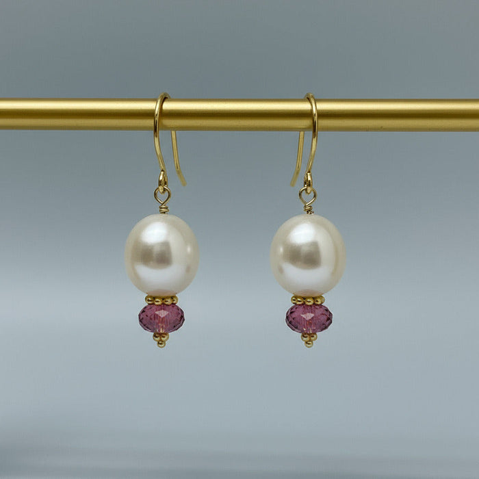 Pair of pearl earrings with pink tourmalines on a gray background