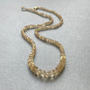 Gold beaded necklace on a gray surface