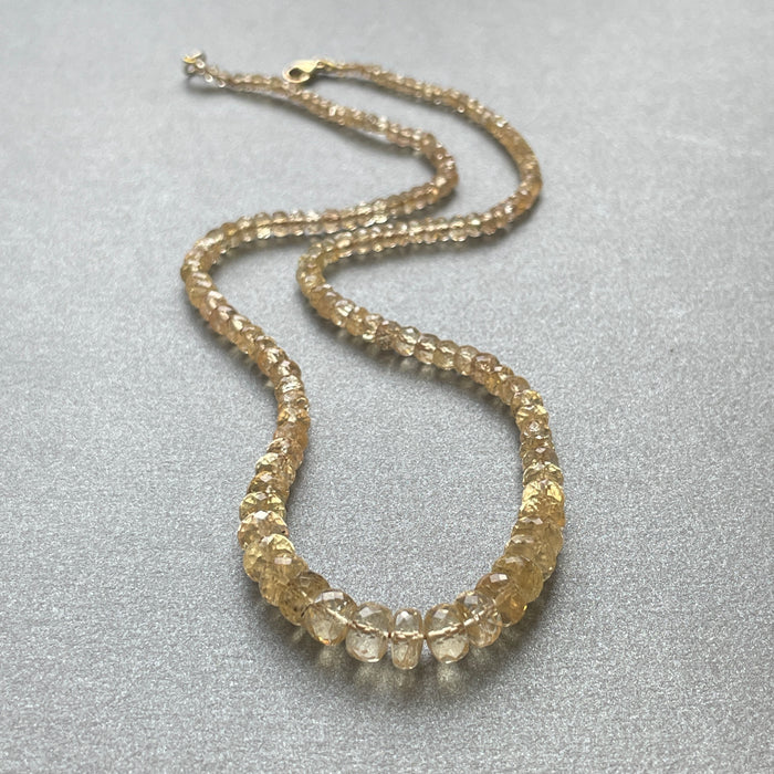 Gold beaded necklace on a gray surface