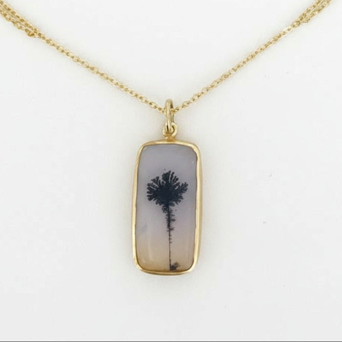 Necklace with a pendant featuring a tree design on a white background