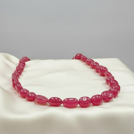 Pink ruby necklace set on a cream satin surface