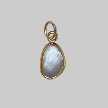 Gold charm with a teardrop-shaped aquamarine on a light gray background