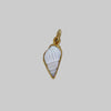 Shell charm with gold frame on a light gray background