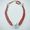 Necklace with orange sapphires and a large white pearl on a white background