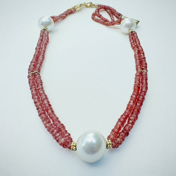 Necklace with orange sapphires and a large white pearl on a white background